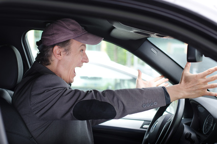 Angry upset man at wheel driving his car screaming