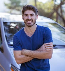 Smiling man with car in background