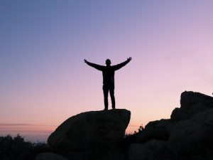 Man with open arms standing on rock